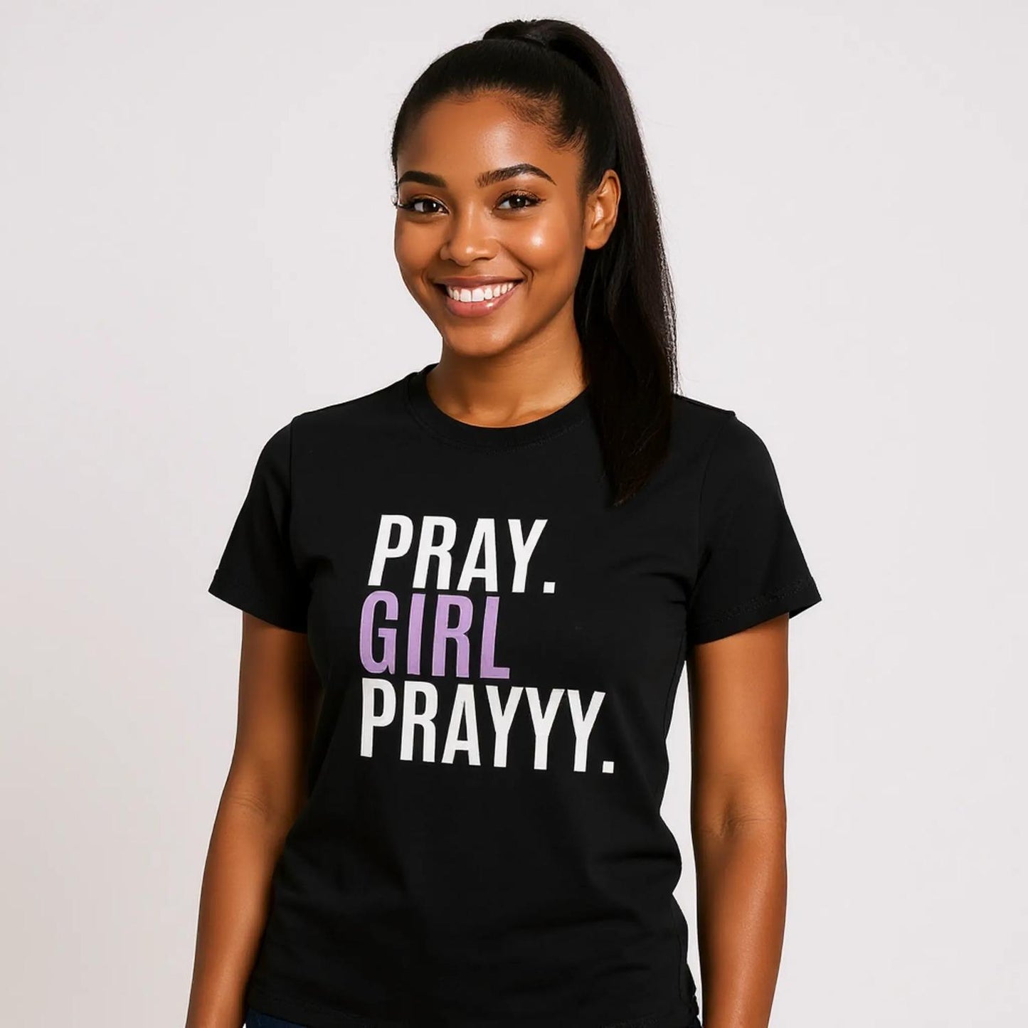 Woman wearing a black t-shirt with 'PRAY. GIRL PRAYYY.' text on a plain background